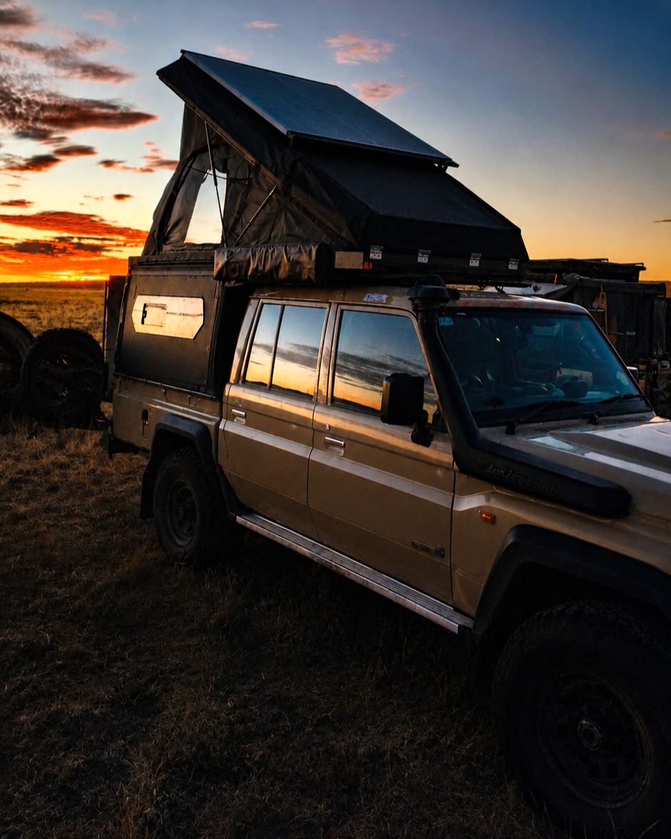 Camping-equipped 4x4 with rooftop tent open at dusk