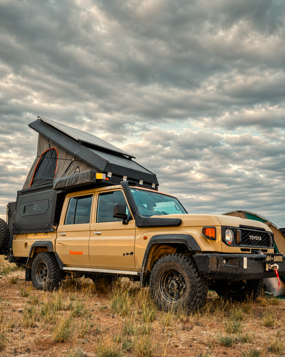 Camping-equipped 4x4 with rooftop tent open under cloudy sky