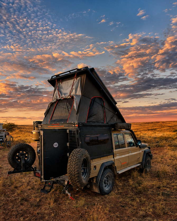 Camping-equipped 4x4 with rear tent setup at sunset