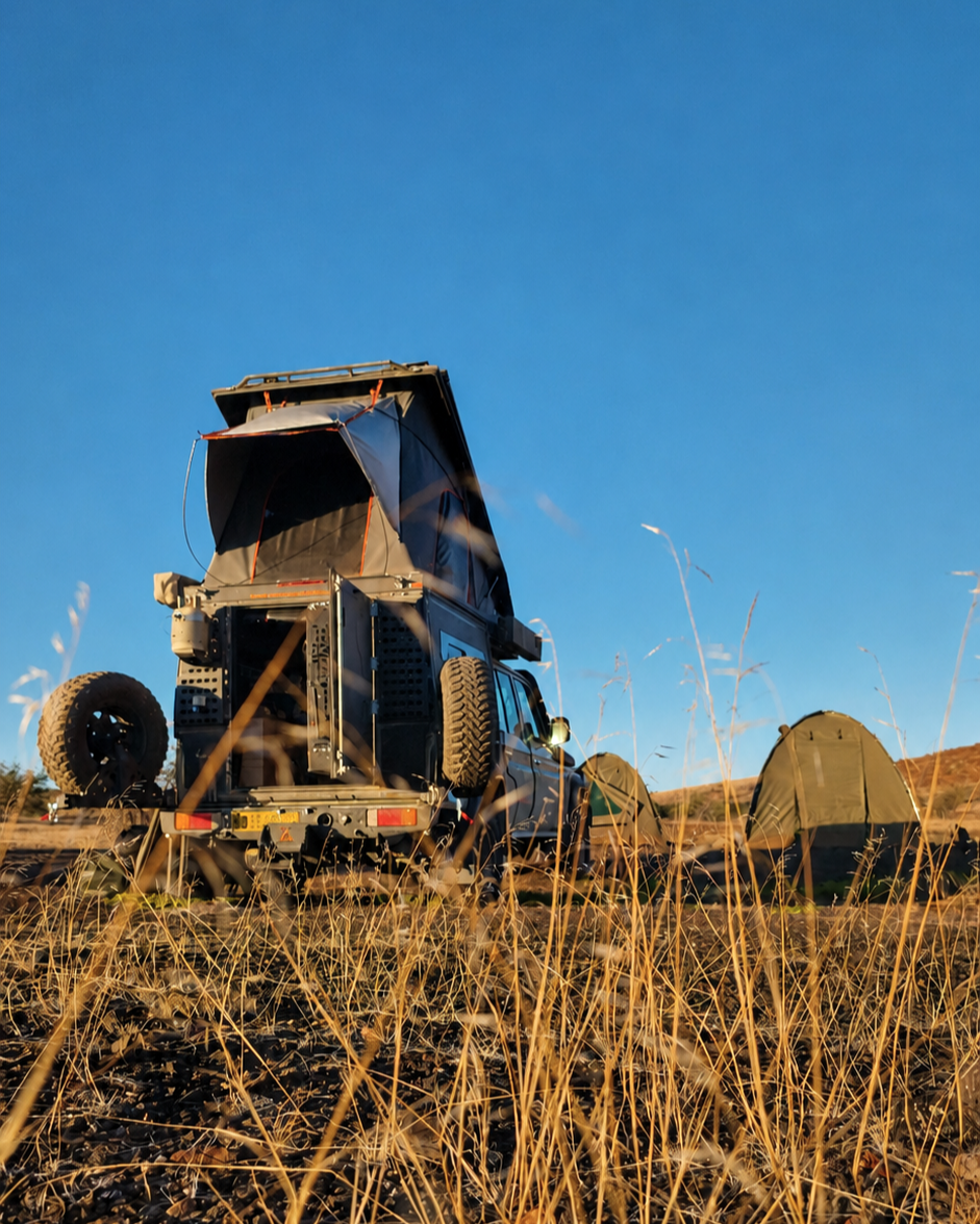 Camping-equipped 4x4 with rooftop tent under blue sky