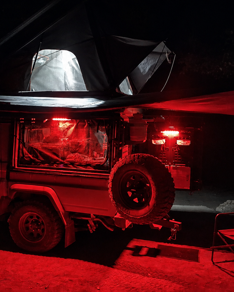 Camping-equipped 4x4 campsite lit red at night