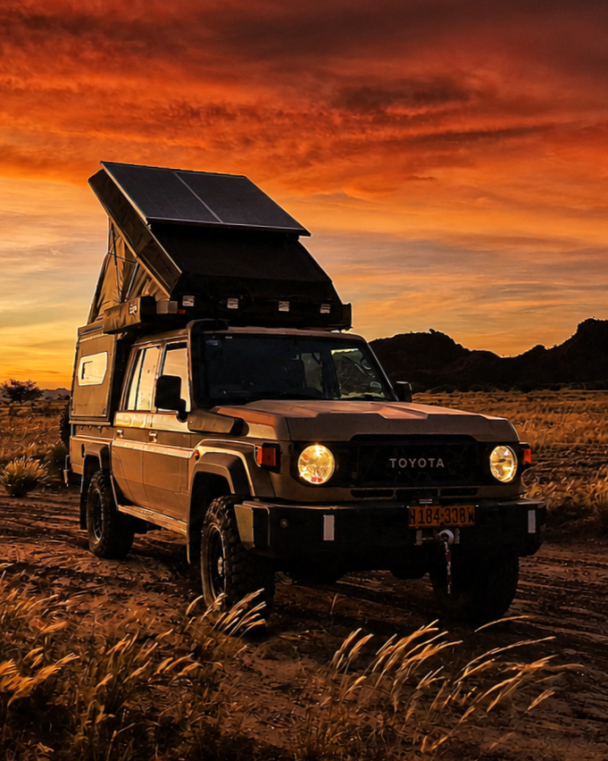Camping-equipped 4x4 facing sunset with rooftop tent open